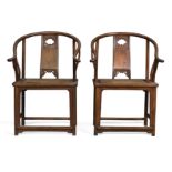A pair of Chinese elm horseshoe back armchairs Late Qing dynasty With curved top rail above cen...