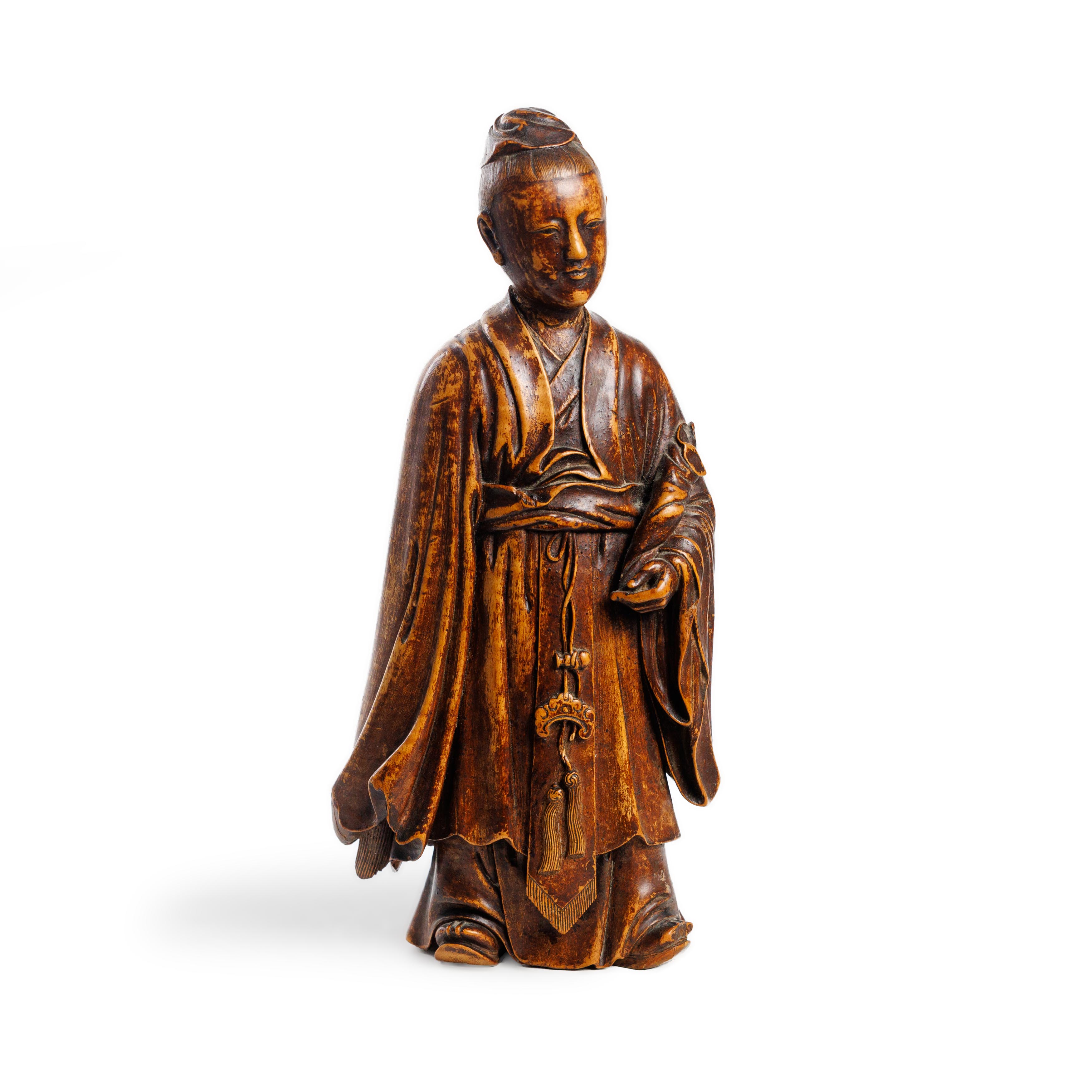 A Chinese wood figure of a scholar Qing dynasty, 18th century Clad in thickly-folded robes and ...