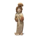 A Chinese pottery figure of a court lady Tang dynasty Modelled standing swaying to the left, he...