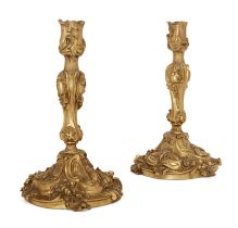 A pair of French gilt-bronze candlesticks, Of Louis XV style, late 19th century, Each cast with s...