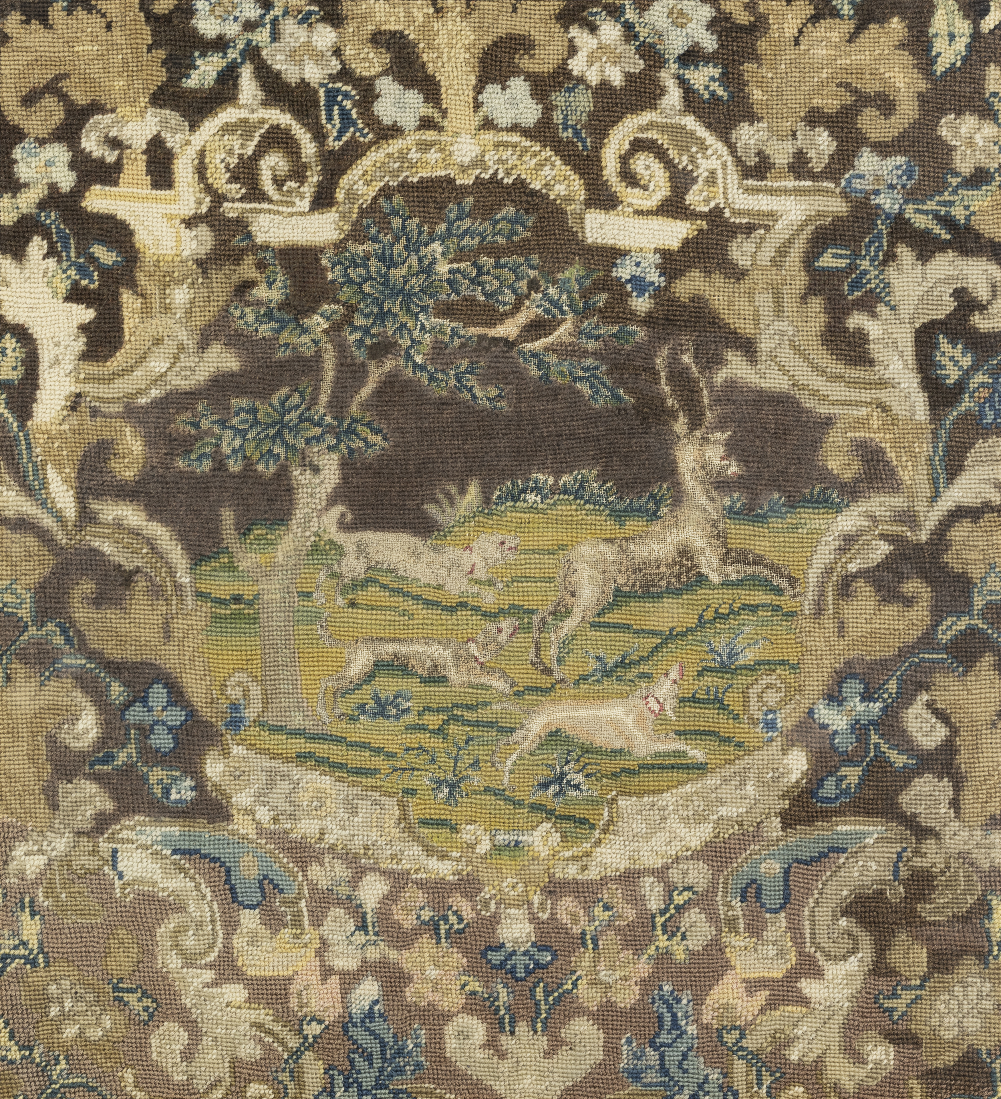 A Continental needlework fragment, 18th century and later, Depicting a stag being pursued by thre...