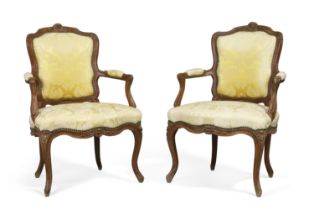 A pair of Louis XV beech framed fauteuils, Third quarter 18th century, With carved floral crest a...