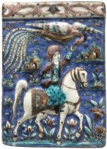 A polychrome moulded equestrian pottery tile, Tehran, Qajar Iran, c.1880, The rider reaching for ...