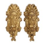 A pair of French ormolu mask mounts, 19th century, Cast as satyr masks with scrolling foliate sur...