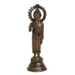 A Burmese bronze figure of Shakyamuni, 18th / 19th century, Cast standing, with flame mandala beh...