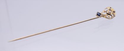 A gold diamond and sapphire stick pin, in box. 6.5 cm long. 1.1 gram total weight.