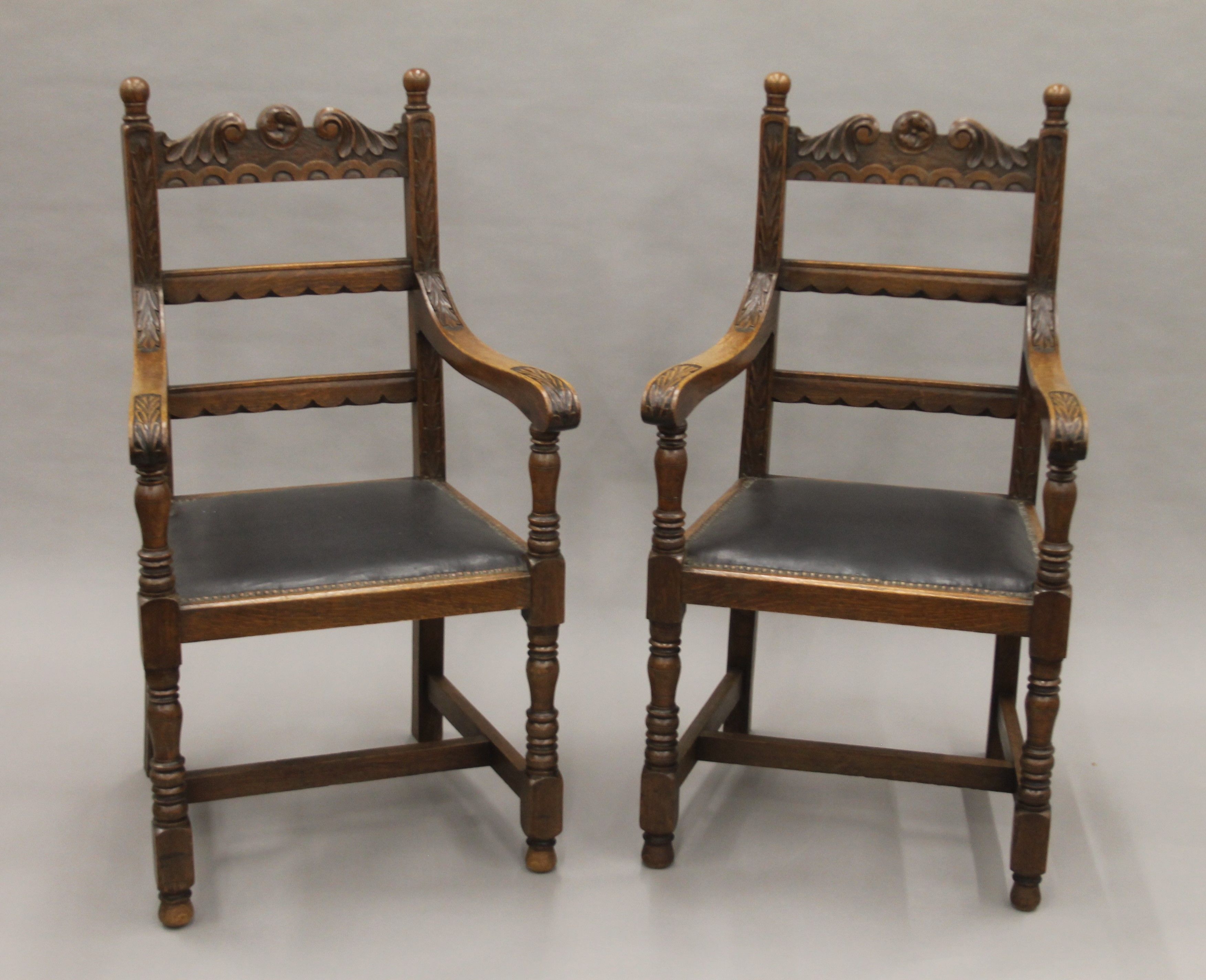 A pair of carved oak open armchairs. Each 57.5 cm wide.