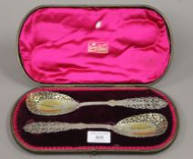 A boxed pair of silver gilt pierced serving spoons. The spoons each 24 cm long. 159.6 grammes.