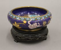 A Chinese cloisonne bowl on wooden stand. 12.5 cm diameter.
