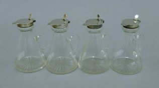 A set of four silver lidded glass toddy jugs. 10.5 cm high.