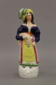 A 19th century Staffordshire figure of a lady wearing a plumed hat and holding a faun whippet under