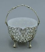 A silver pierced basket with milk glass liner. 12.5 cm wide. 187.3 grammes of silver.