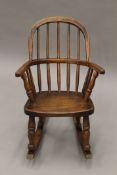 A Victorian elm child's stick back open arm rocking chair.