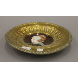 A 19th century Continental painted porcelain dish with brass surround. 32.5 cm diameter.