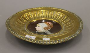 A 19th century Continental painted porcelain dish with brass surround. 32.5 cm diameter.