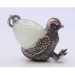 A pendant formed as a chick carrying an egg, bearing Russian marks. 3 cm high.