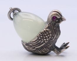 A pendant formed as a chick carrying an egg, bearing Russian marks. 3 cm high.