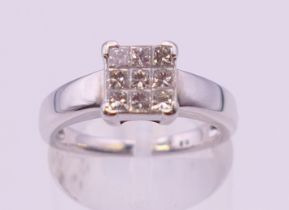 An unmarked 18 ct white gold square set nine stone diamond ring. Ring size L.