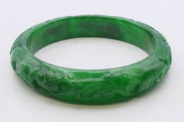 A carved apple green jade bangle. Approximately 5.5 cm internal diameter.
