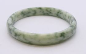 A two-tone speckled jade bangle. Approximately 6 cm internal diameter.