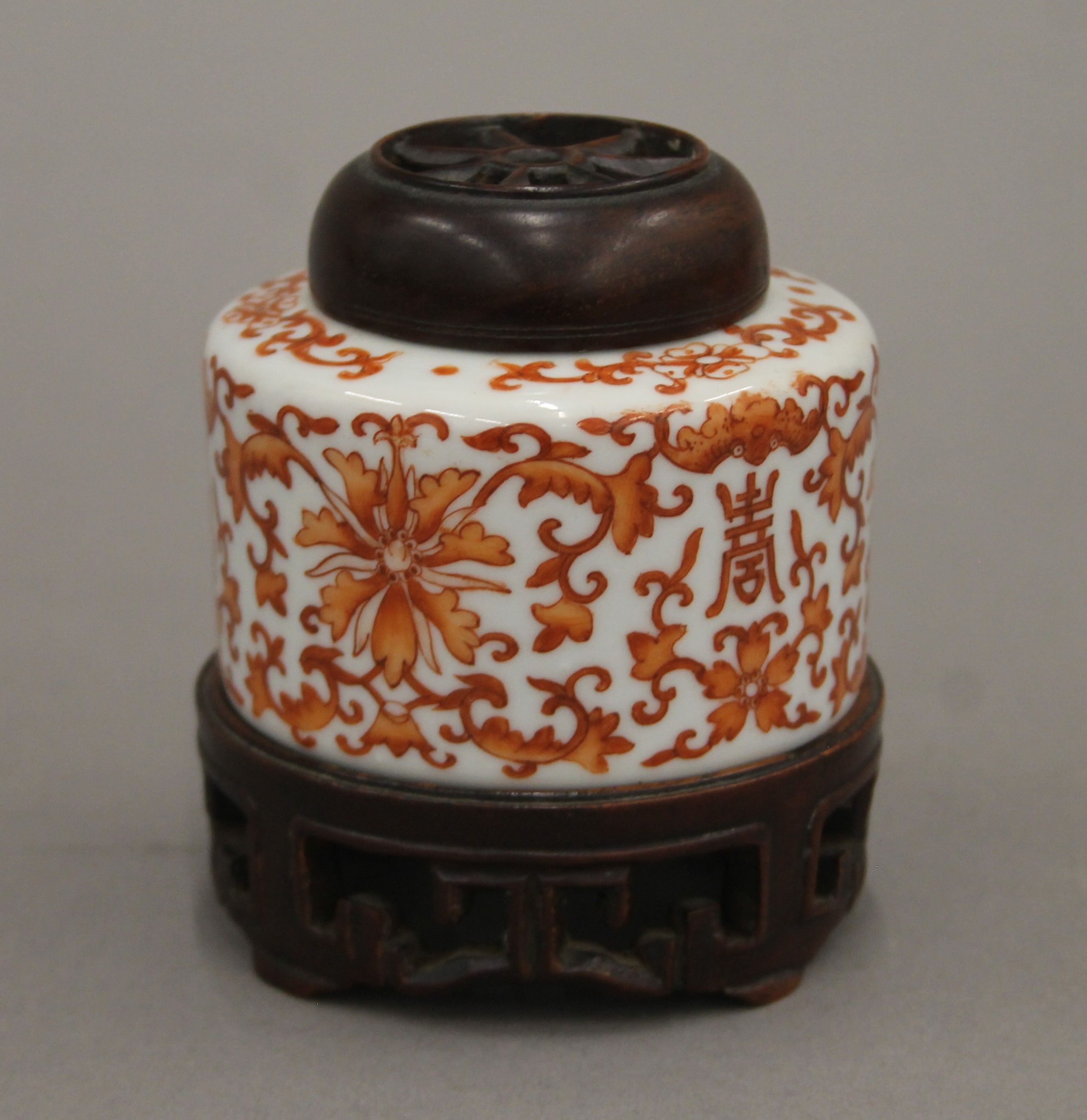 A Chinese porcelain jar with carved wooden lid and stand. 9 cm high overall.