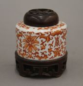 A Chinese porcelain jar with carved wooden lid and stand. 9 cm high overall.