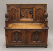 A carved oak box settle with lion form arms. 105 cm wide.