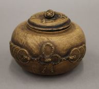 A Chinese Yixing lidded pot decorated with coins, seal mark to the base and lid. 10 cm diameter.