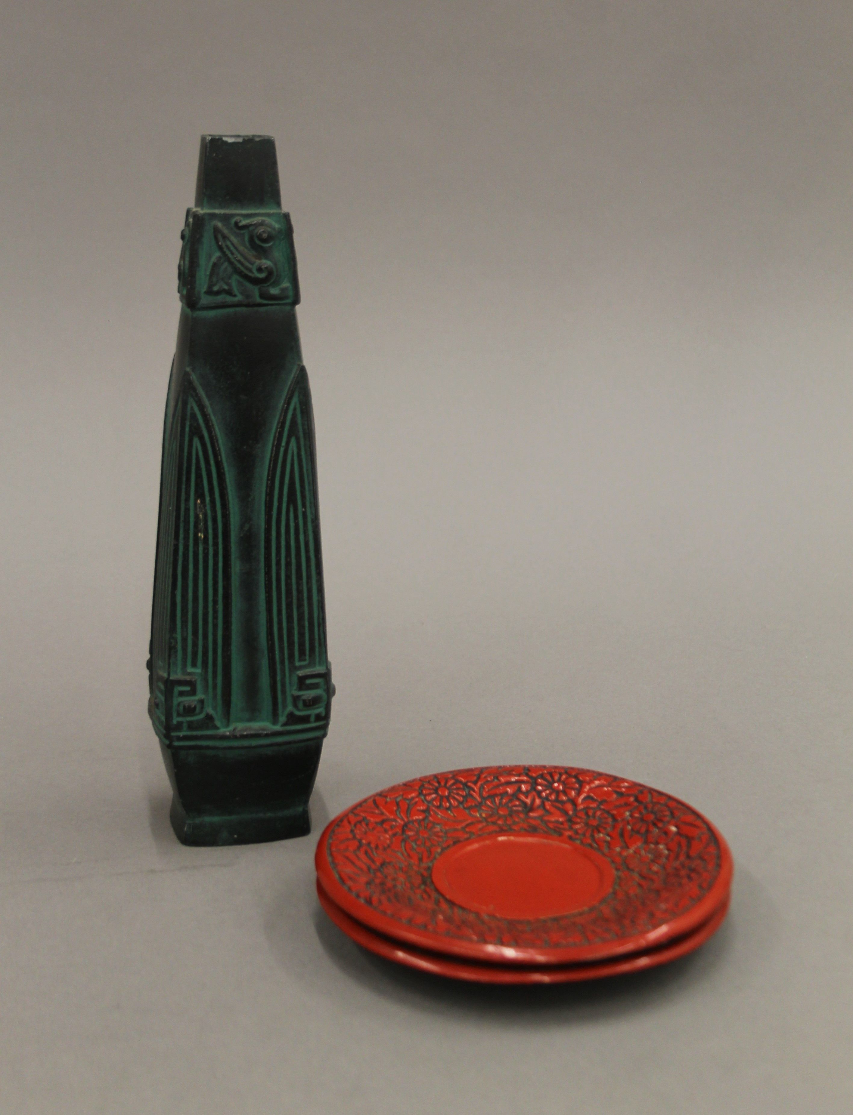 An Oriental bronzed vase and two cinnabar saucers. The former 25 cm high.