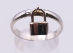 An unmarked silver ring set with a padlock. Ring size T/U.