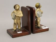 A pair of early 20th century mahogany bookends each surmounted with a painted spelter of a model of