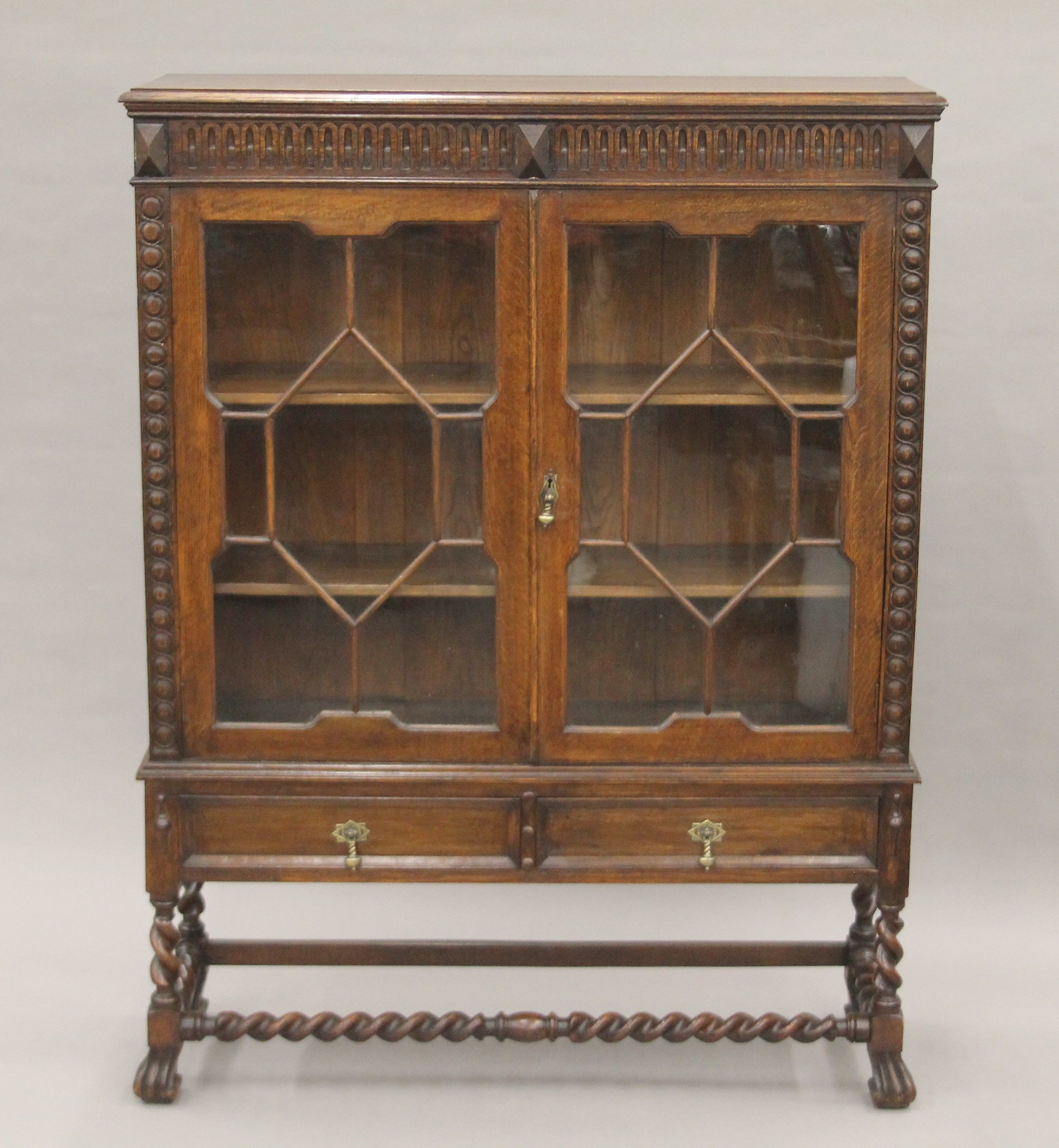 An early 20th century carved oak two door glazed barley twist cabinet. 105 cm wide.