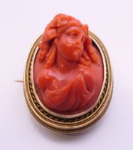 A 15 ct gold carved coral brooch. 3.25 cm high. 14.4 grammes total weight.