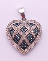 A 10 ct white gold diamond and sapphire heart form pendant. 2.75 cm high. 3.2 grammes total weight.