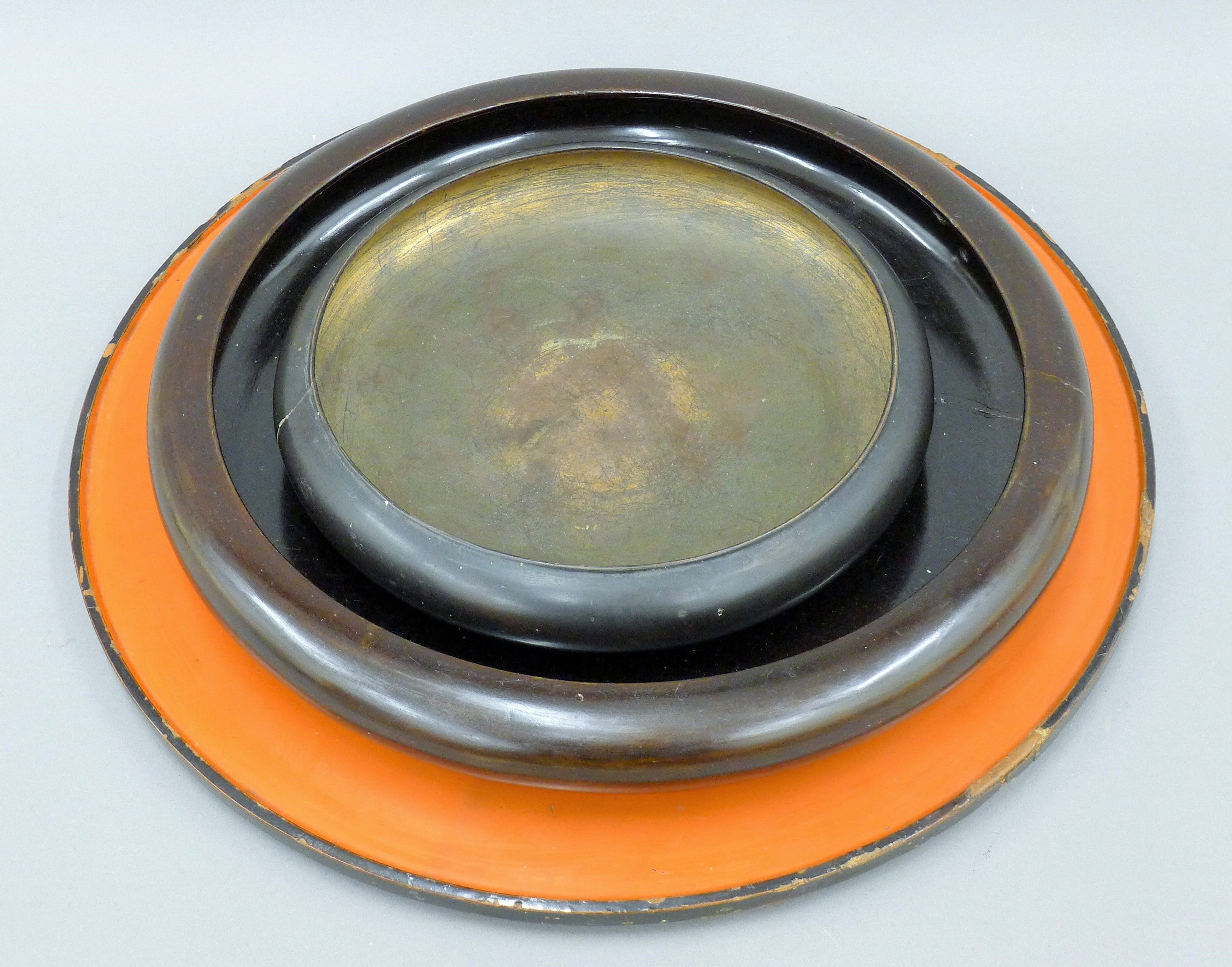 Two Oriental shallow lacquered dishes and a lacquered tray. The latter 40 cm diameter.