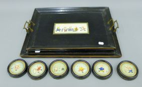 A pair of early 20th century ebonised trays and six matching coasters,