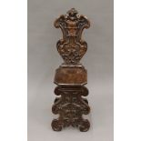 A 19th century carved walnut Sgabello chair, the shaped back worked with a vacant heraldic shield,