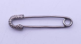 A diamond set safety pin. 3 cm long.