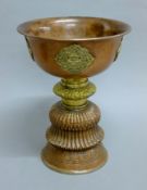 A late 19th century large Tibetan copper and brass butter lamp with silver base rim.