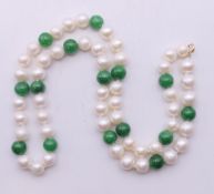 A string of pearls and jade beads with 14 ct gold clasp. 44 cm long.