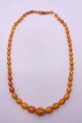 An amber bead necklace. 72 cm long. 65.9 grammes total weight.