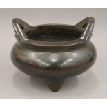 A Chinese twin handled bronze censer of circular form on three feet, seal mark to base.