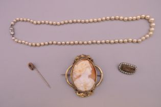 A cameo brooch, a pearl necklace, a mourning brooch and a horseshoe form stick pin.