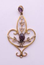An Art Nouveau amethyst and seed pearl 9 ct gold pendant on a chain. The pendant 5 cm high.
