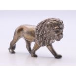 An unmarked white metal model of a lion. 6 cm long.