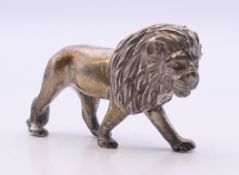 An unmarked white metal model of a lion. 6 cm long.