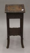 A small carved oak two tier side table. 30 cm square.