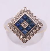 An Art Deco style 18 K white and yellow gold diamond and sapphire ring. Ring size P.