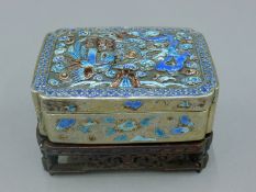 A 19th century Chinese silver and enamel box mounted on pierced wooden stand. 11.5 cm long. 248.