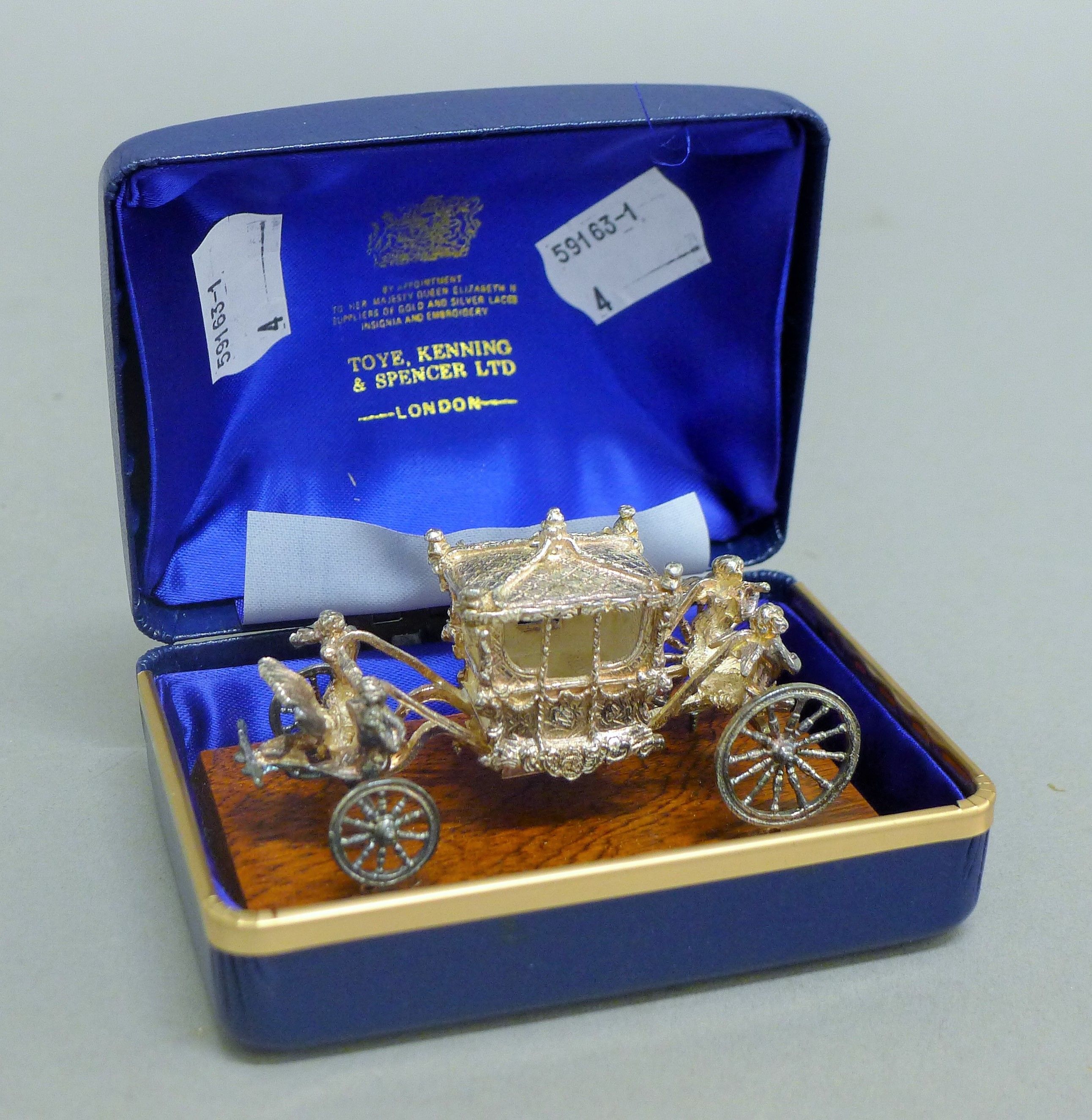 A boxed Queen Elizabeth II Silver Jubilee silver coach on wooden plinth. The plinth 8.5 cm long.